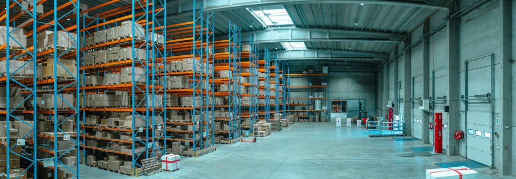 Tall blue metal racking filled with cardboard boxes in a large warehouse, showing storage height