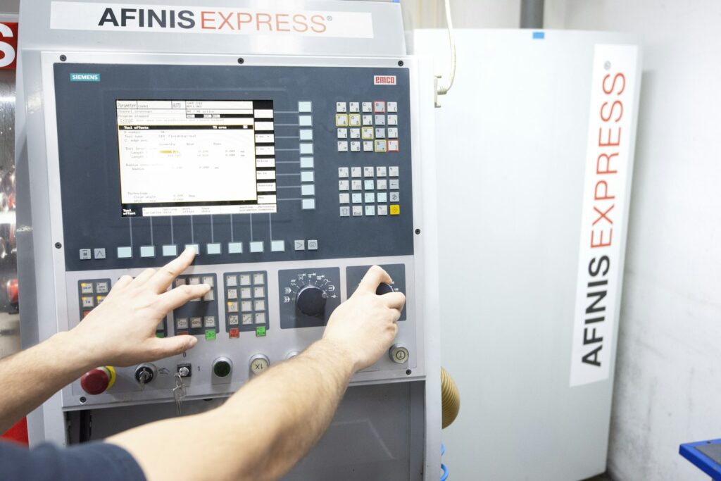 Man operating a machine in a factory, as a new operator learns the controls