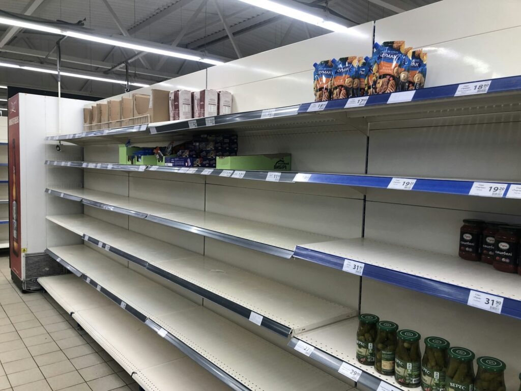 Row of empty shelves in a grocery store, showing the stock gaps a field visit can find