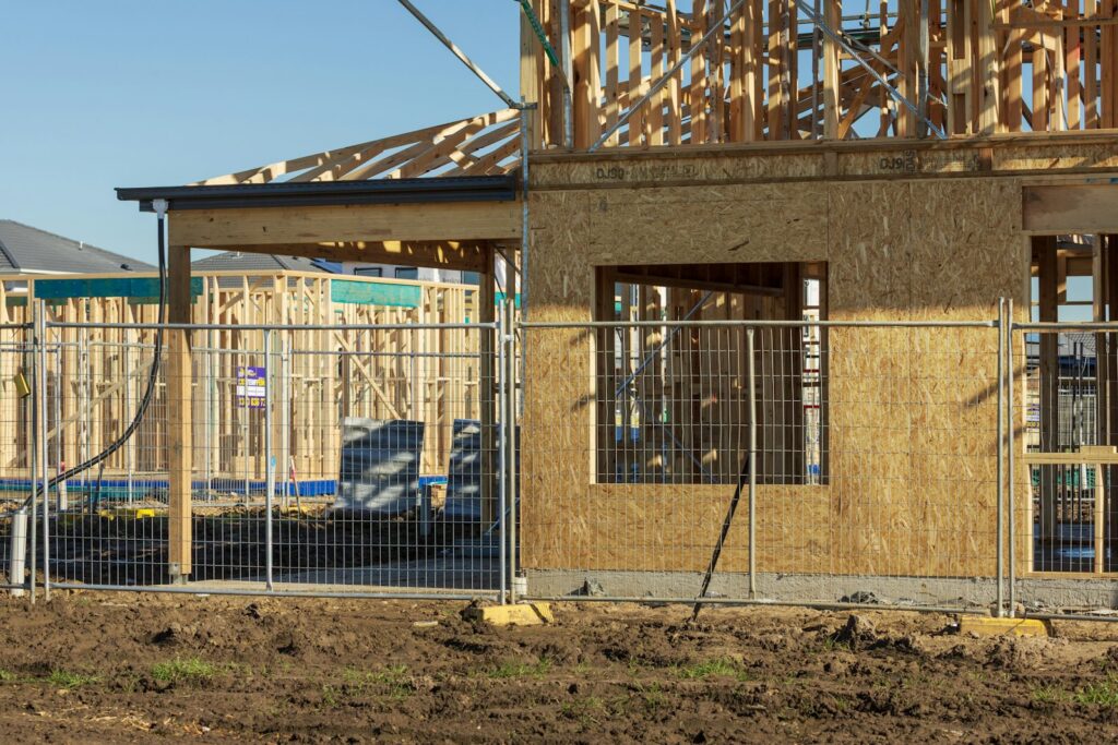 New house under construction with a wooden framework and temporary fencing around the site
